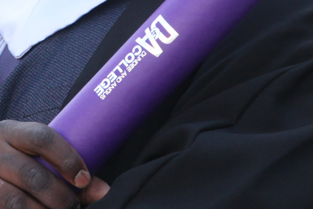 Student hand holding graduation scroll