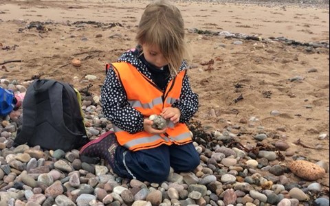 child playing with pebbles on beach