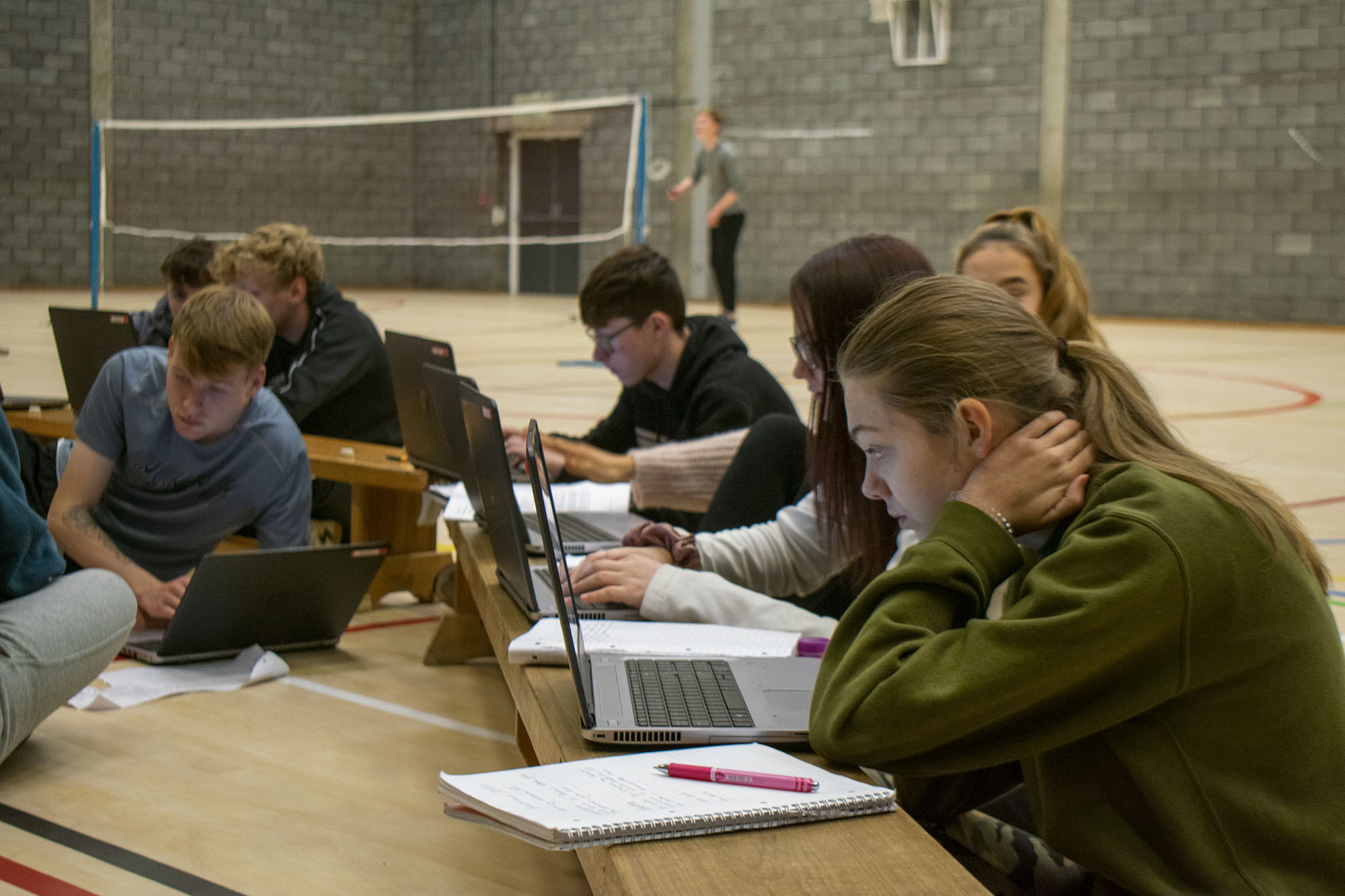 students at laptops in a gym hall