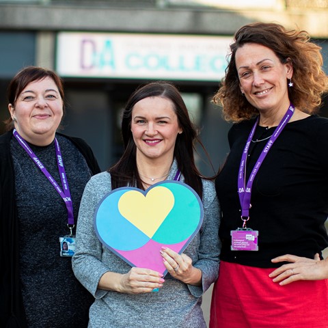 College staff holding a heart logo