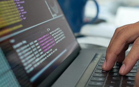 Hands typing on a laptop