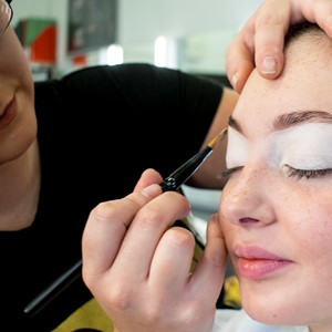 Student applying makeup to a female face