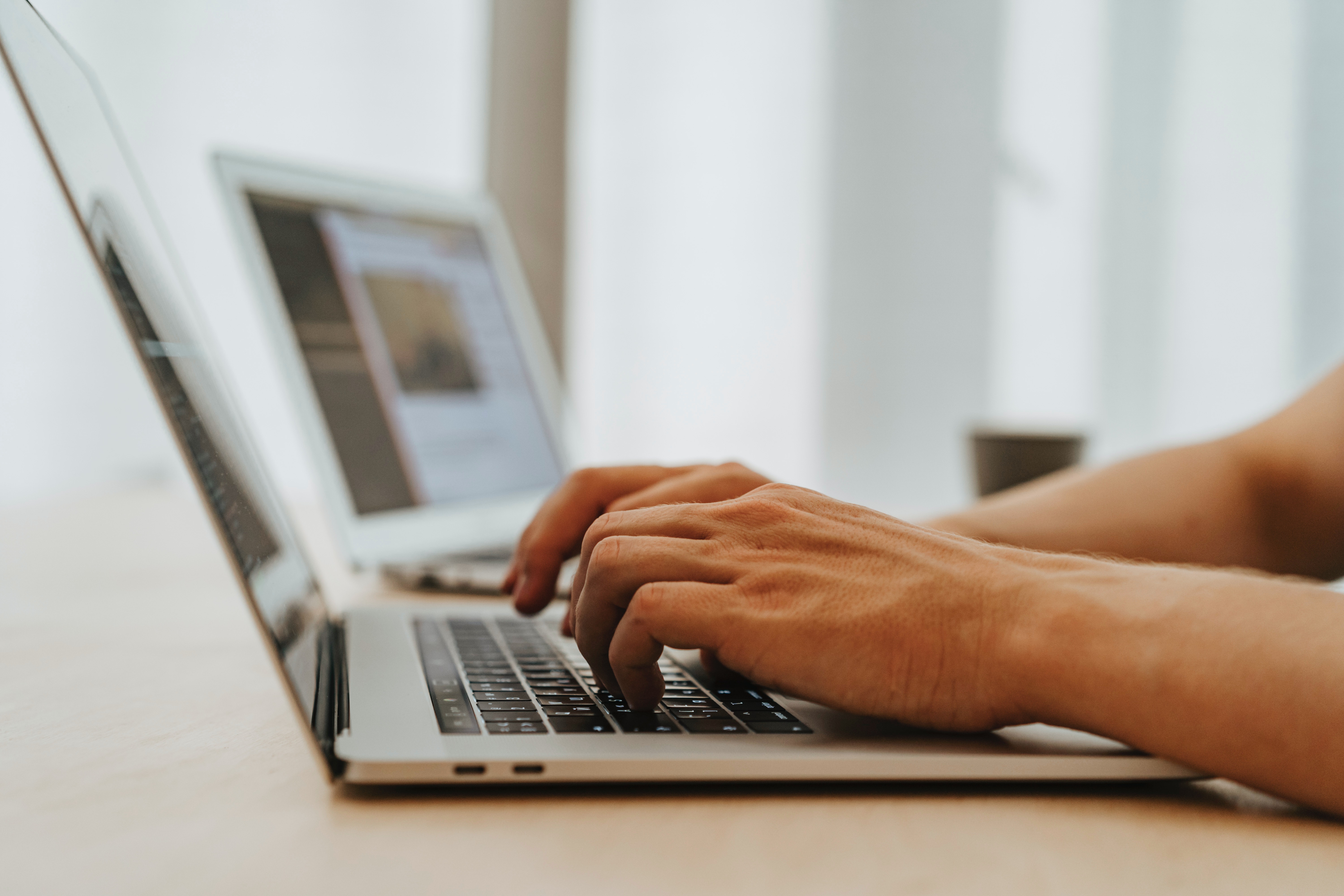 side view of hands typing on a laptop
