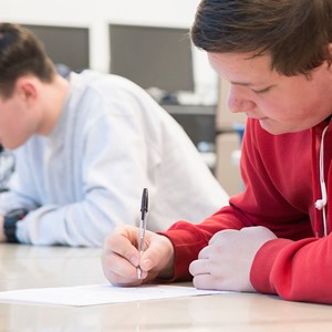 Student in classroom writing on paper