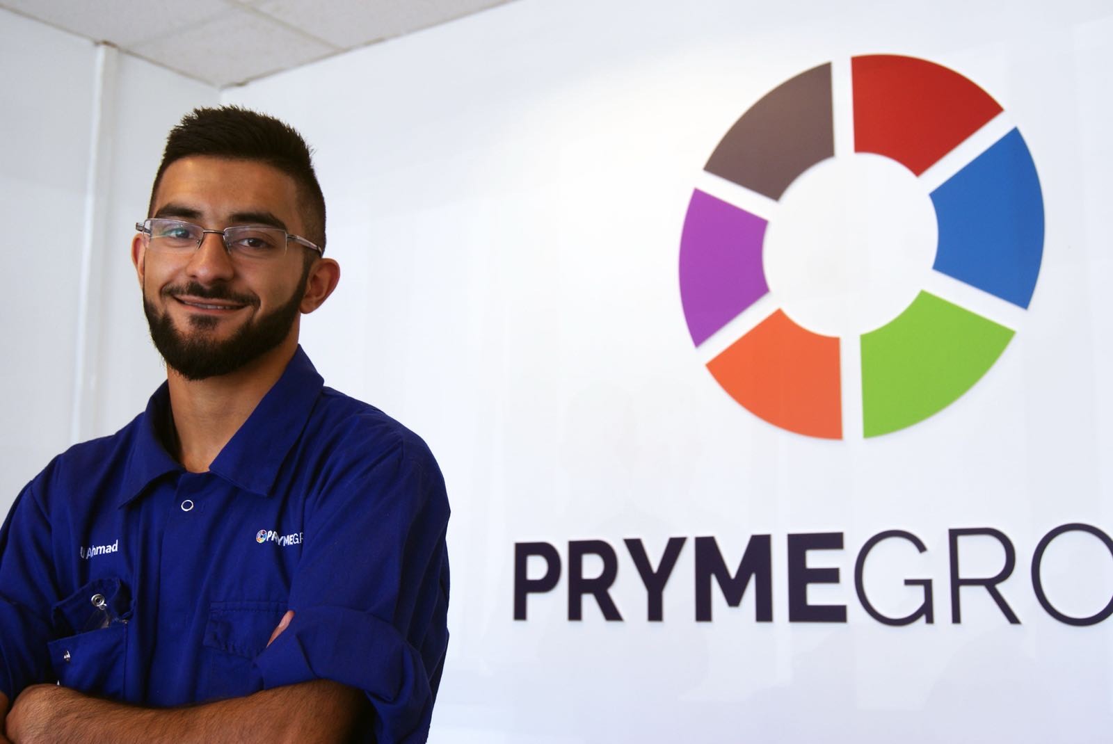 Usman Ahmad posing by Pryme group sign