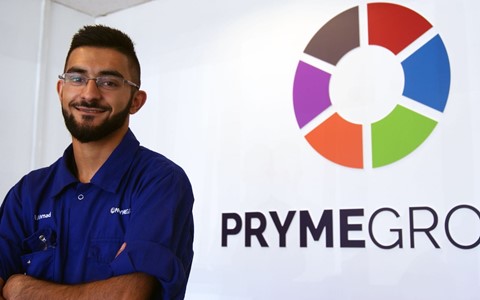 Usman Ahmad posing by Pryme group sign
