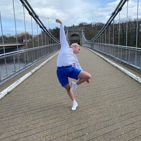 Dancer Nicole Anderson doing a ballet pose on an old suspension bridge