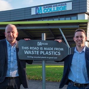 Billy Grace and Simon Hewitt beside sign stating road made from waste plastics