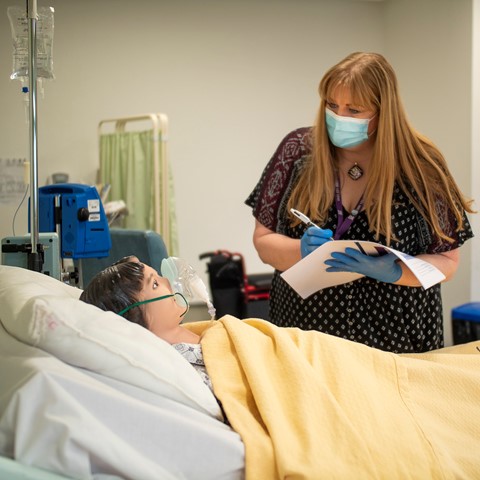 Nursing student practicing checkup on medical dummy