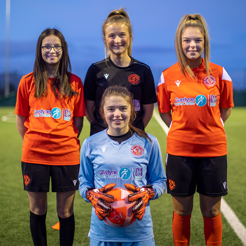 Girls football team members wearing all of the different kit colours.