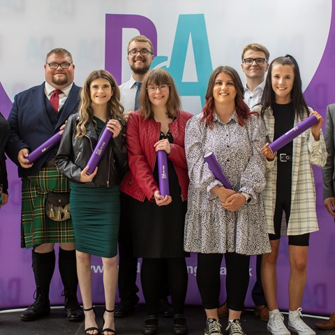 DFN Project SEARCH interns on stage at their graduation with Lecturer Leanne Macdonald and Principal Simon Hewitt