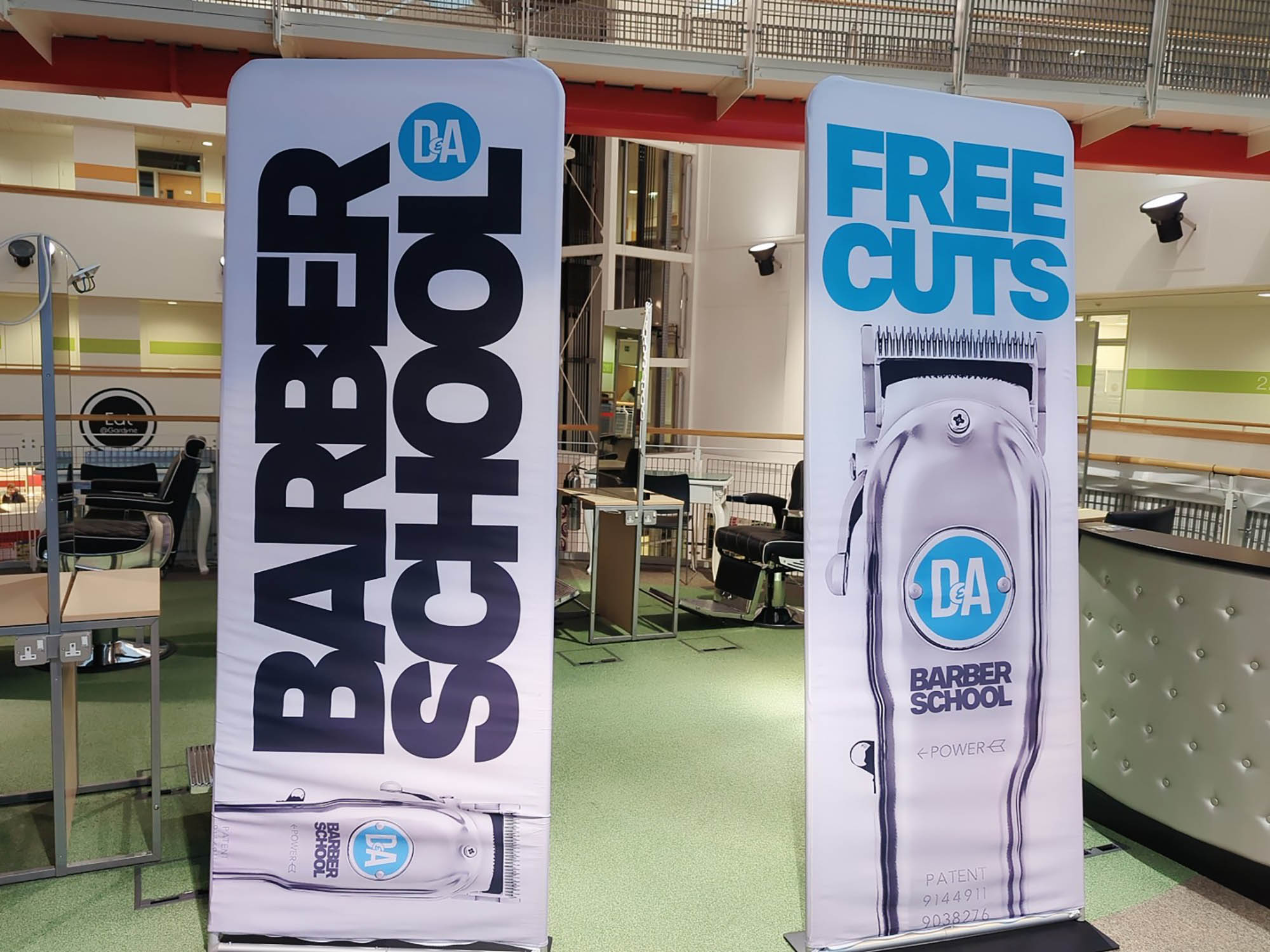 Photo of two pop up banners for D&A Barber School & free haircuts)