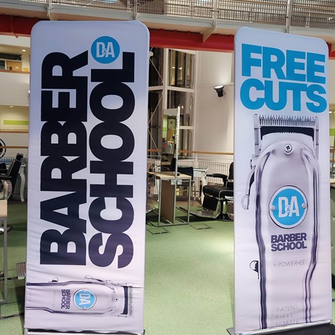 Photo of two pop up banners for D&A Barber School & free haircuts