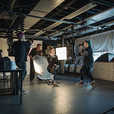 Students in photography studio taking woman's photo