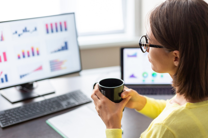 woman looking at digital dashboard holding mug of coffee
