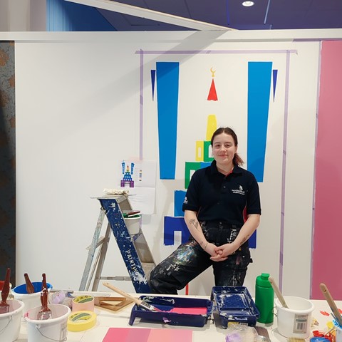 student posing in front of painting as part of WorldSkills competition