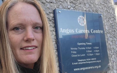 woman standing at a sign for Angus Carers Centre