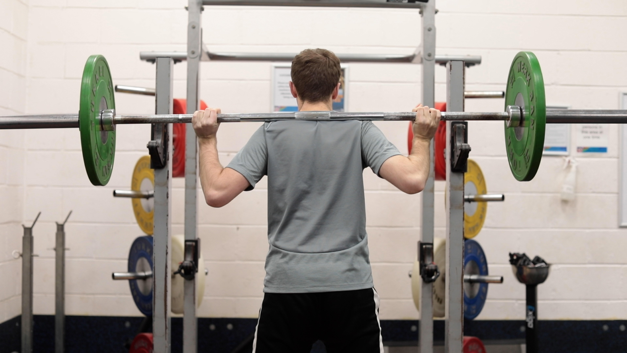 Student doing weight training with a bar