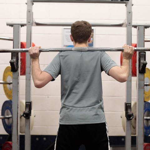 Student doing weight training with a bar