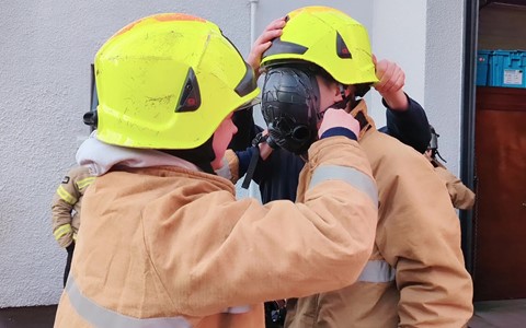 Students putting firefighter helmet on another student