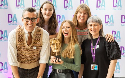 Group photo of BAFTA and D&A College members of staff posting with BAFTA trophy