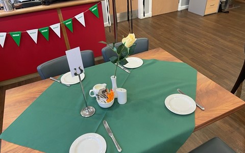 table set up for coffee morning with green table cloth, side plates and knives.