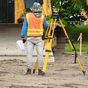Student standing with surveying equipment