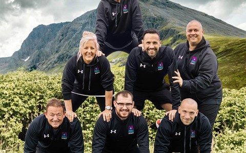 Seven members of the Sports and Fitness Team at Dundee and Angus College in a pyramid shape in front a mountain