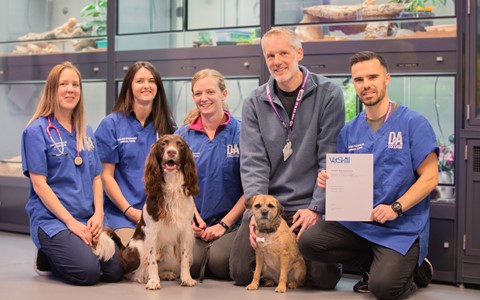 D&A Staff with their dogs proudly holding the VetSkill Centre Certification in front of six large aquariums