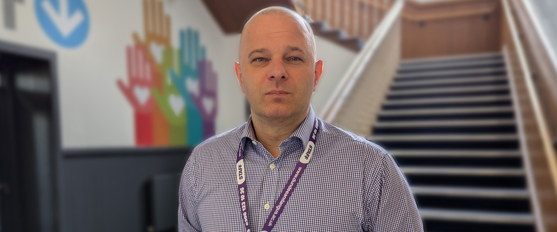 Rafal standing in front of staircase and wall with hands and hearts