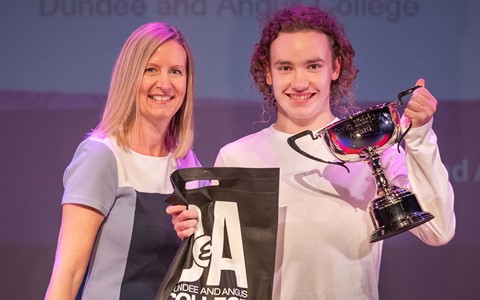 Student holding trophy and goodie bag next to Dundee and Angus College Vice Principal