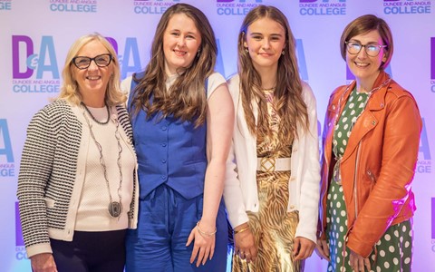 Two students standing beside two women posing for photo against Dundee and Angus College backdrop