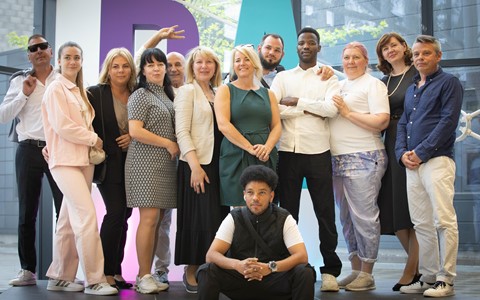 a group of ESOL students standing in front of giant D&A letters