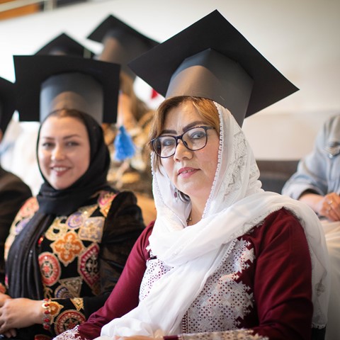 ESOL students sitting wearing graduation caps that they made from cardboard