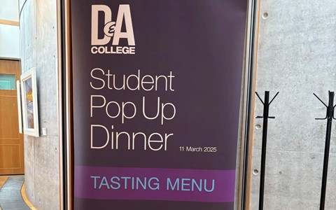A vertical promotional banner for D&A College's Student Pop Up Dinner on 11 March 2025. The banner includes the D&A College logo at the top, followed by the event title and date. A purple box labeled 'TASTING MENU' appears in the center. The lower section states that the meal is prepared and served by SVQ Level 3 Professional Cookery and HNC Hospitality & Professional Cookery students, supervised by D&A College lecturing staff. Contact details include the website www.dundeeandangus.ac.uk and pho