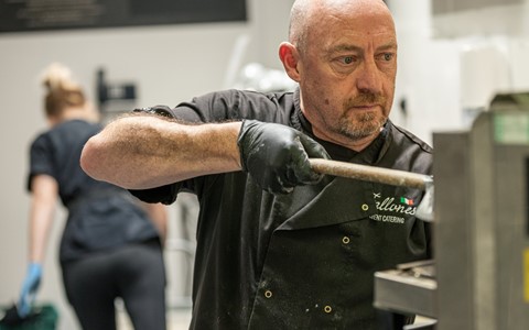A person putting a pizza in a pizza oven