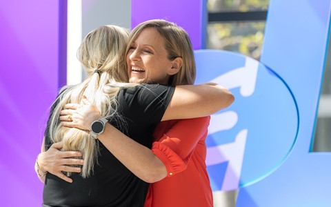 two members of staff hug on stage after one wins an award
