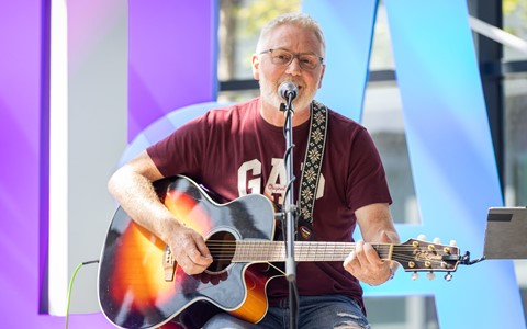 A staff member plays guitar on stage