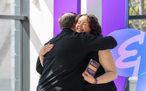 Staff members hug on stage as they collect their award