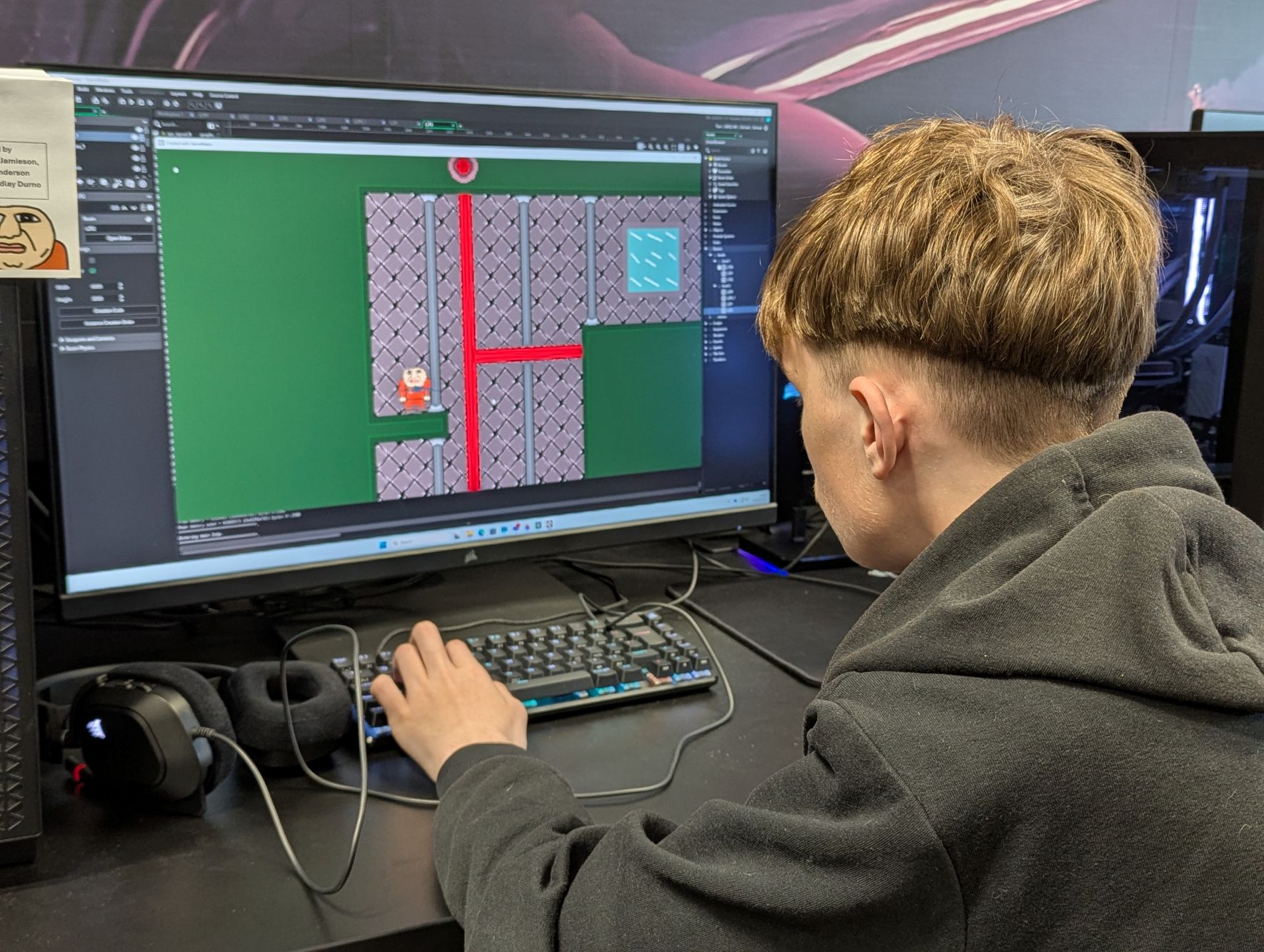 A student sitting at a PC creating a game