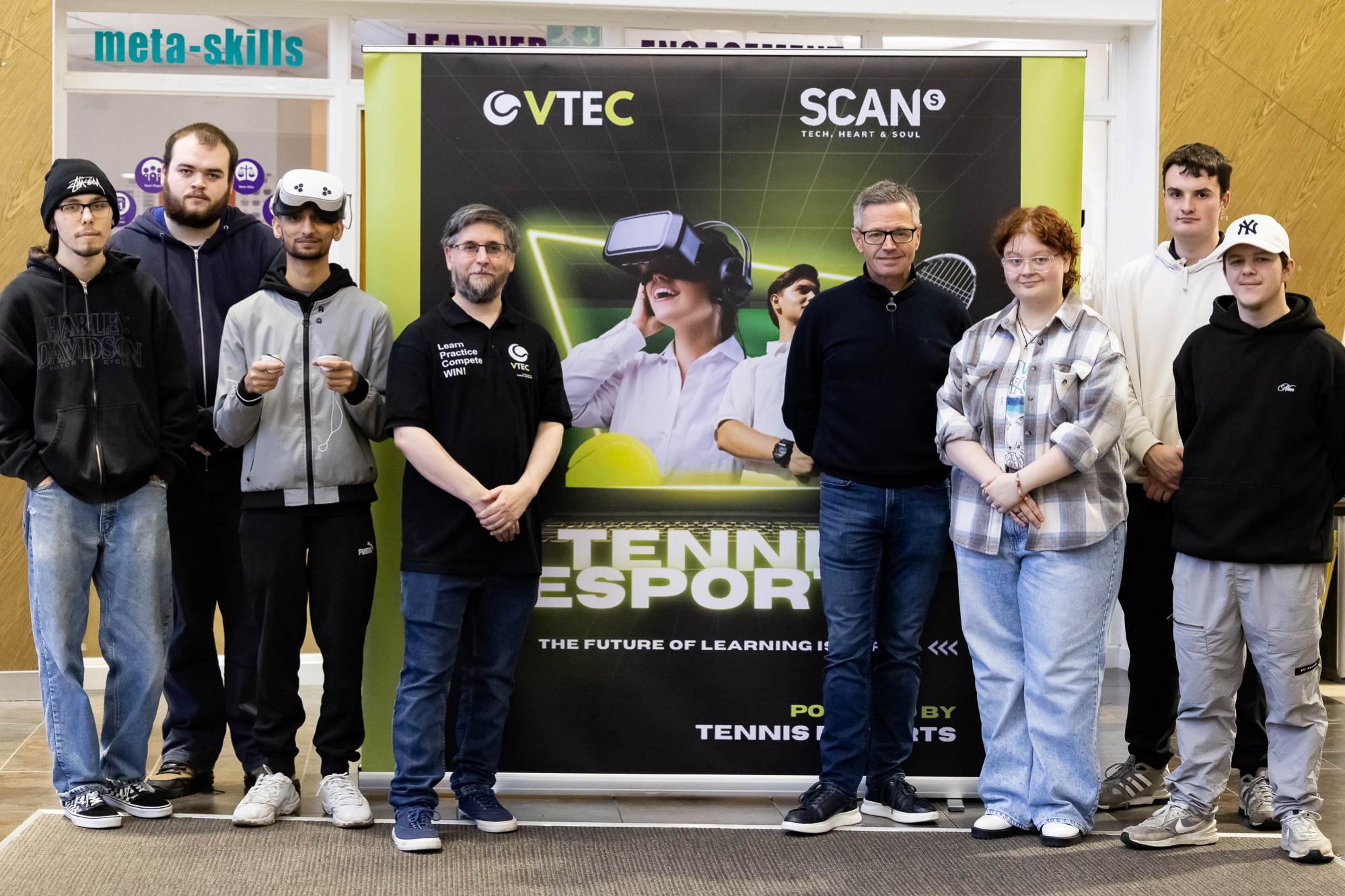 Group of people standing in front of a banner featuring VTEC and SCAN logos, promoting VR tennis and esports.)