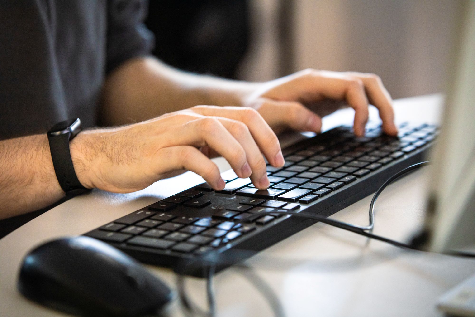 hands typing on a computer keyboard
