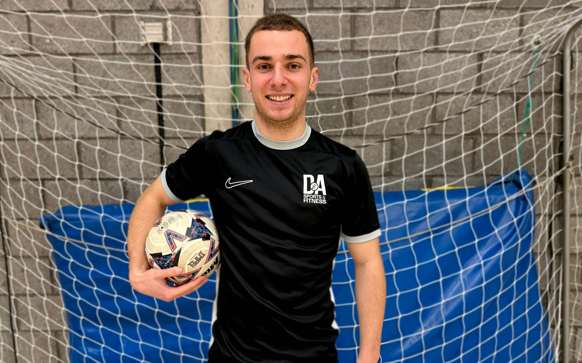 Sports student standing holding ball in front of goal