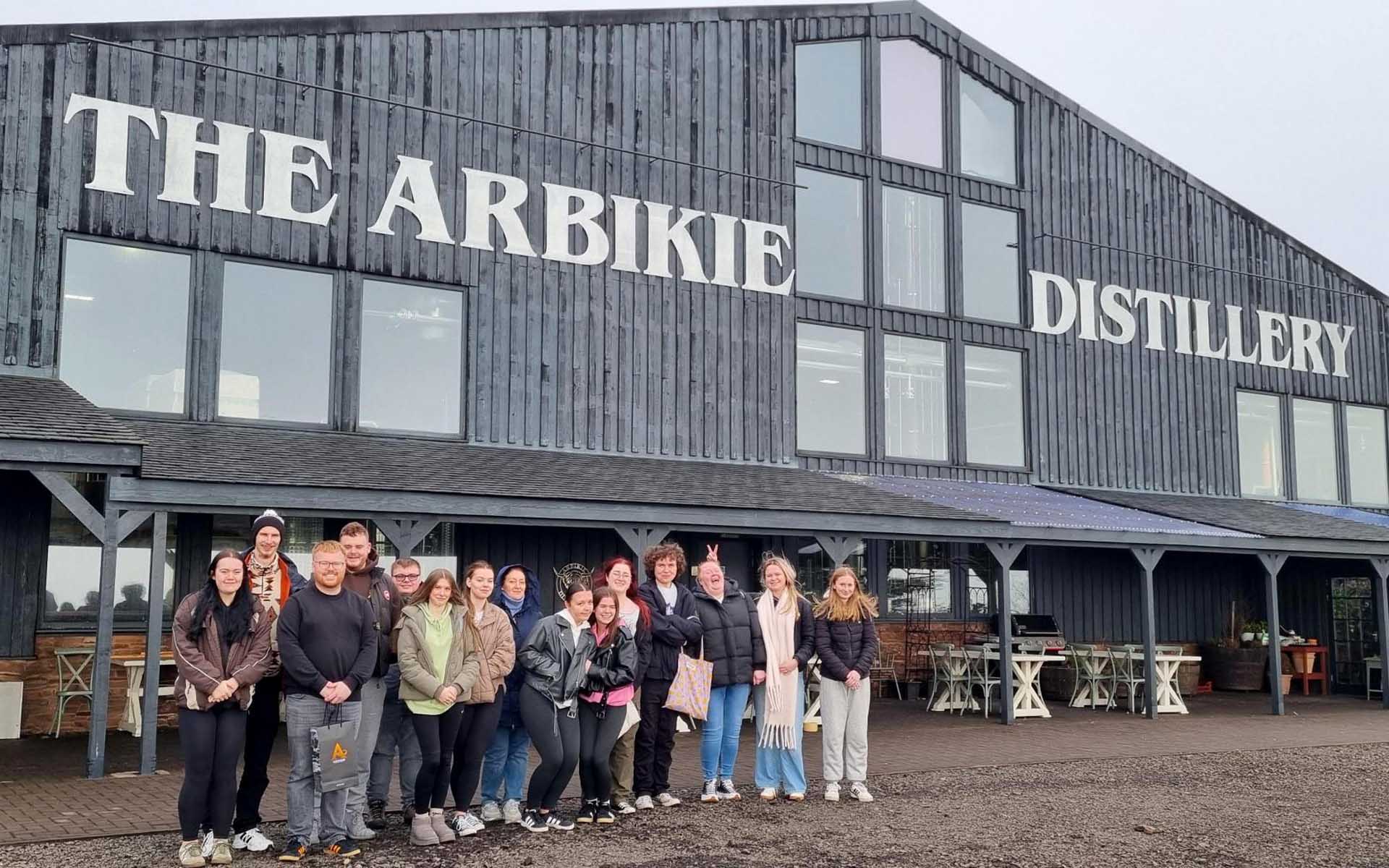 Group of students smiling in front of distillery