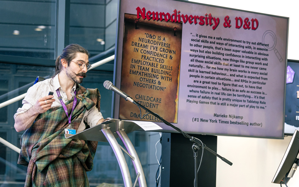 Staff member in kilt on stage leading presentation at Dungeons and Dragons Summit Event