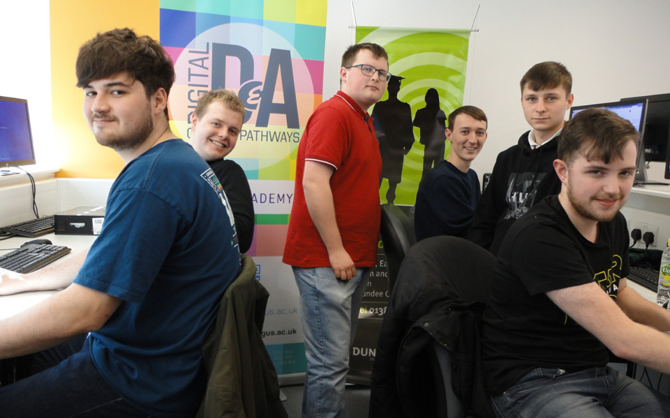 Computing students gathered around computers smiling for photo