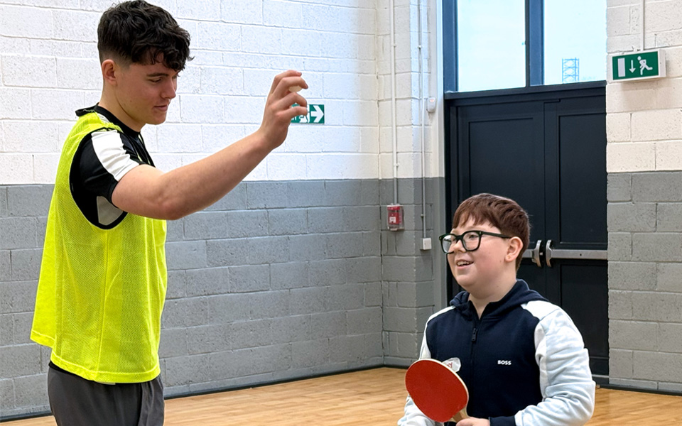 Student about to about to bounce table tennis ball for school pupil holding paddle
