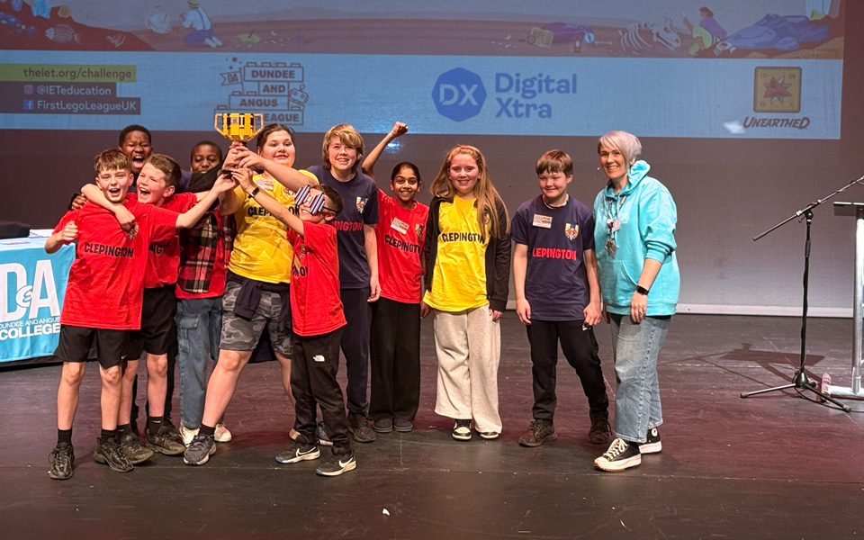 Team of school pupils holding lego trophy on stage