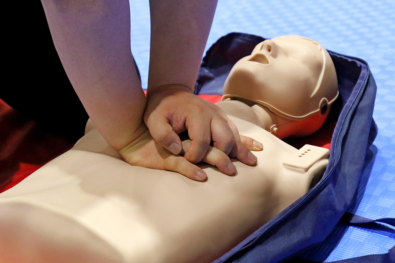 Person's hands performing CPR on dummy