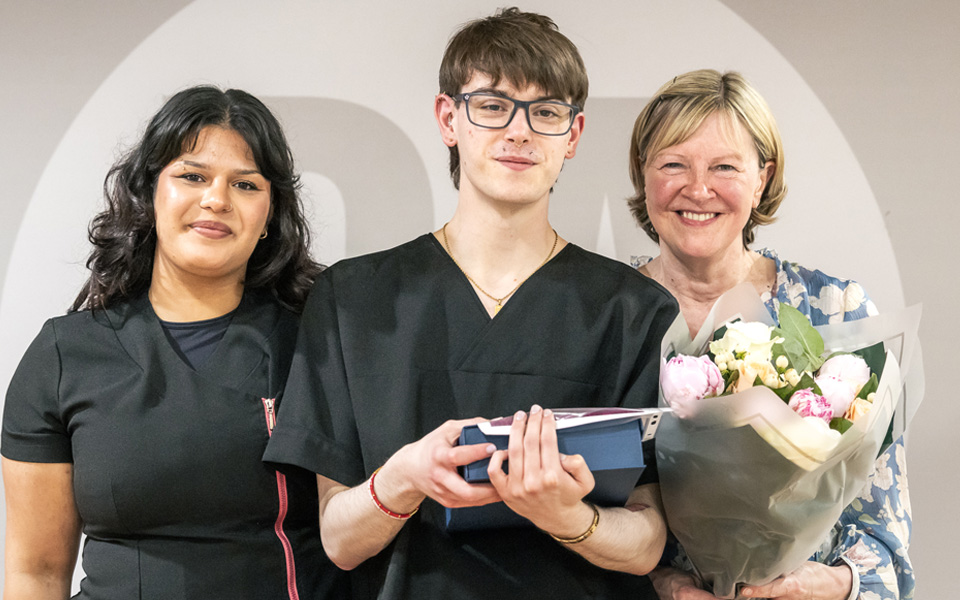 Student prizewinner holding prizes with guests holding flowers